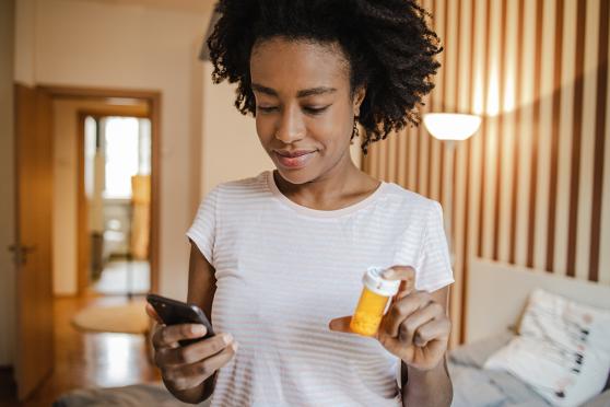 Women looking at device while holding pill bottle